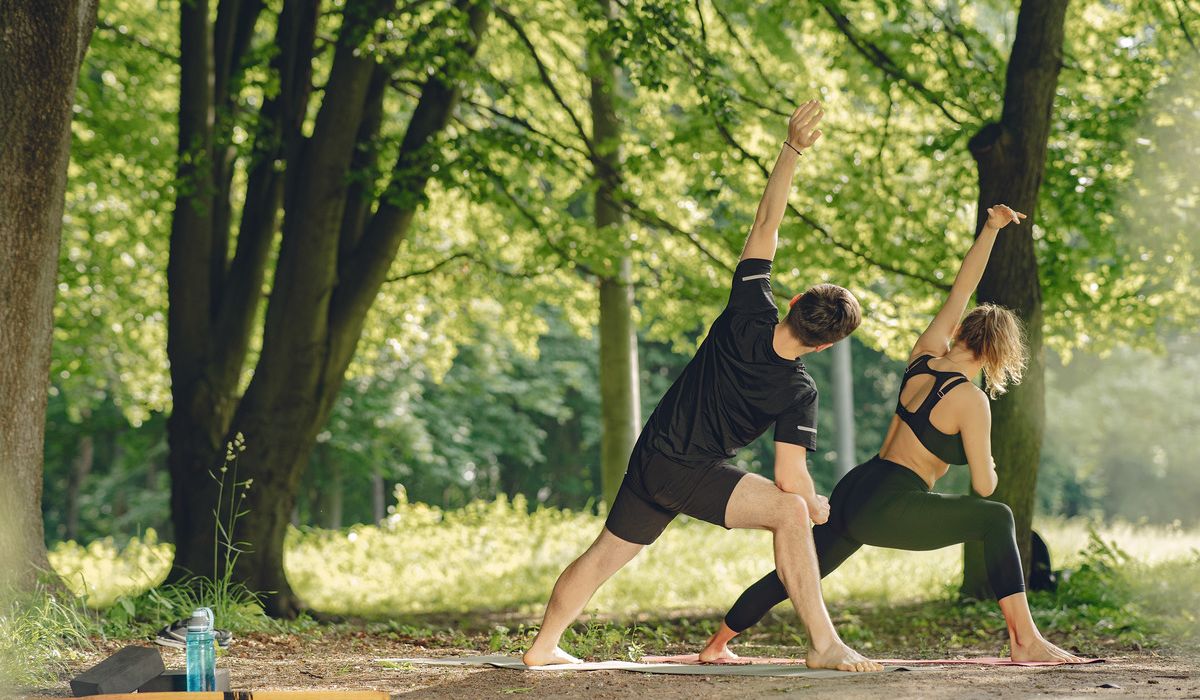 Young sportive couple doing yoga fitness people summer park