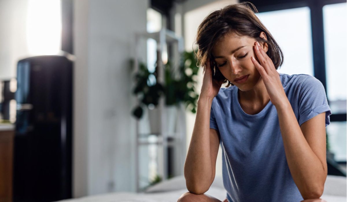 woman holds head in pain