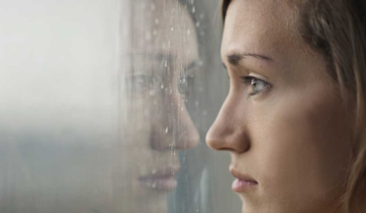 Woman looking through a window in the rain